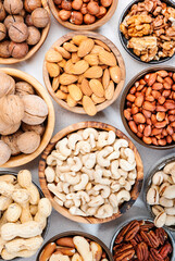 Nuts in bowls. Almonds, hazelnuts, walnuts and other. Healthy food snack mix on white table, top view