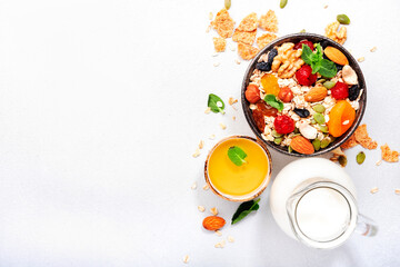 Muesli bowl and ingredients for healthy breakfast. Granola, nuts, dried fruits, flakes, honey and greek yogurt on white tableб copy space