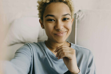 Close-up of cute African ethnicity girl recording stories for her blog using selfie camera of her...