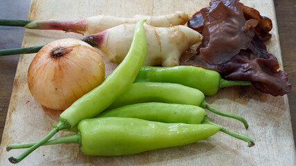 Close-up of green bell peppers and vegetables on a wooden cutting board.