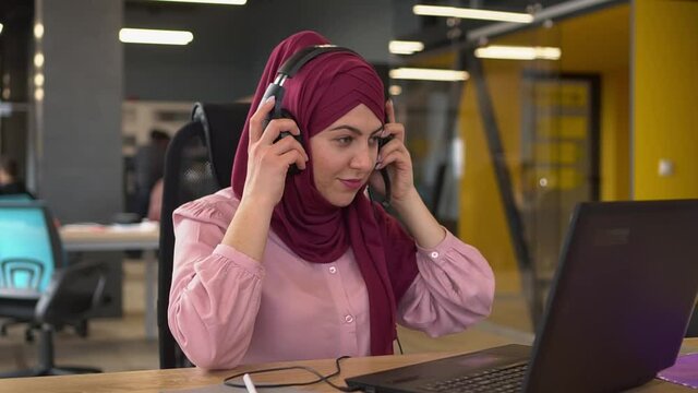 Muslim business woman in hijab with headphones and microphone are working in the office. Arab businesswoman working in customer service center using headset