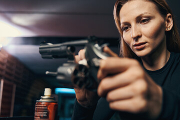 Professional concentrated female sniper cleaning her six-shooter