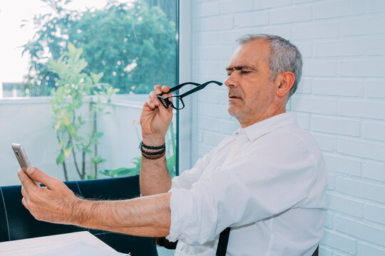 mature man with mobile phone and presbyopia or myopia