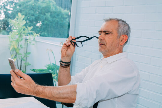 mature man with mobile phone and presbyopia or myopia