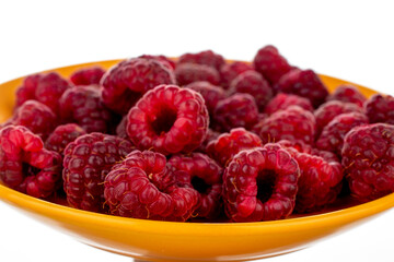 Several berries of ripe red raspberries on a yellow ceramic saucer, close-up, isolated on white.
