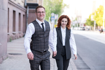 Stylish and redhead husband and wife are walking on the street