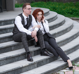 Redhead husband and wife sit on the steps in the street