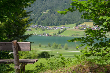 idyllic view of the lake "Weissensee" from a clearing with a wooden bench in the foreground