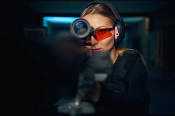 Fototapeta premium Focused woman firing a machine gun with a telescopic sight