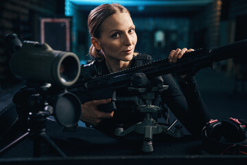 Obraz na płótnie Canvas Calm attractive female sniper posing for the camera indoors
