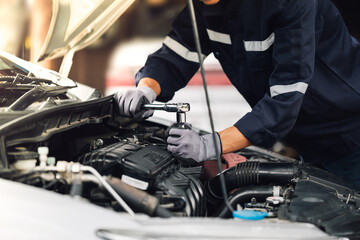 Obraz premium Mechanic works on the engine of the car in the garage. Repair service. Concept of car inspection service and car repair service.