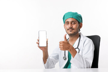 Young indian doctor showing smartphone screen over white background.