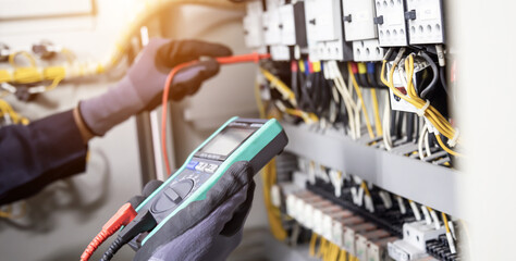 Electrician engineer tests electrical installations and wires on relay protection system. Adjustment of scheme of automation and control of electrical equipment. - obrazy, fototapety, plakaty