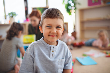 Portrait of small nursery school boy indoors in classroom, looking at camera.