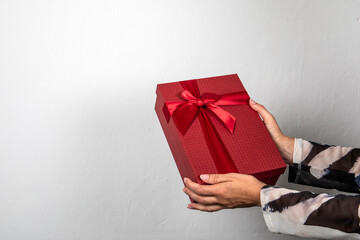 Red gift box in woman's hands. Christmas, birthday or Valentine's Day concept