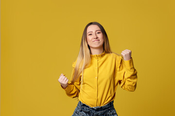 woman showing victory gesture on yellow background.