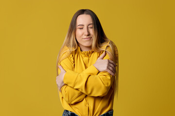 blonde woman hugging oneself happy and positive