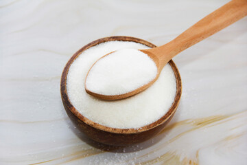 white granulated sugar in a wooden spoon