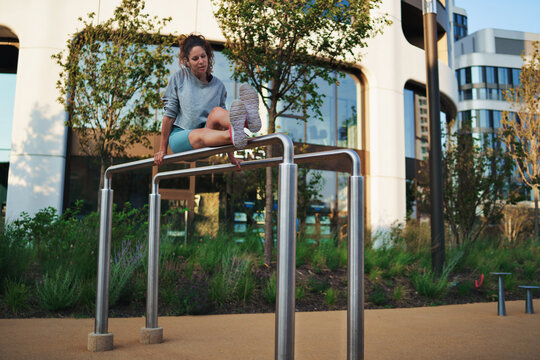 Mid adult woman doing exercise on parallel bars outdoors in city, healthy lifestyle concept.
