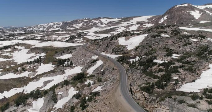 Aerial view of car slowly going up on a curvy mountain road near Beartooth Pass summit in Wyoming