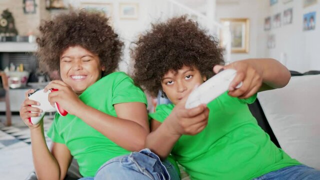 Twin brothers playing computer game with gaming console
