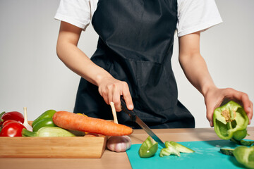 Woman in black apron slicing vegetables kitchen cooking food
