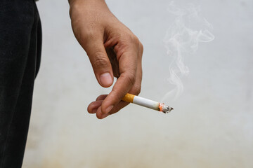Woman holding smoking a cigarette in hand. Cigarette smoke spread.