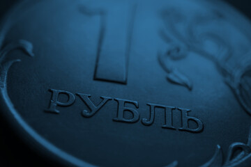 Translation: ruble. A fragment of the Russian coin in 1 one ruble. The name of the national currency of Russia close-up. News about economy, money and banks. Dark blue background or wallpaper. Macro