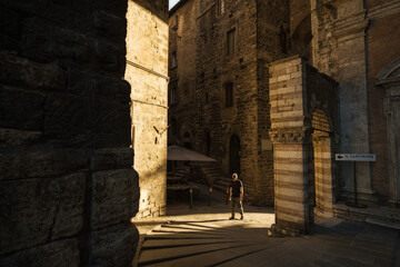 A young man walk into the streets of Perugia during sunset