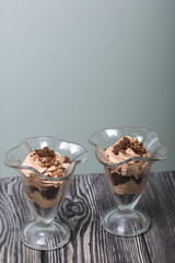 Dessert with cream and biscuit crumbs. Stands on pine boards. Close-up shot.