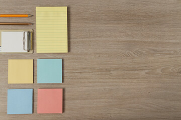 Yellow,blue,pink blank paper,pencils on the wooden desk.Empty space
