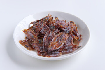 Dried squid salty snack in ceramic plate, Isolated on white background, Preservation or Processed of sea food asian style, Ingredients for seasoning and flavoring soup to make it smell good.