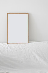 Empty picture frame on a white wall above a white sofa.
