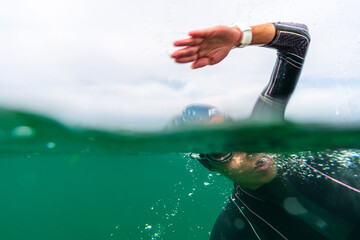 Athlete in a wetsuit swims in a lake