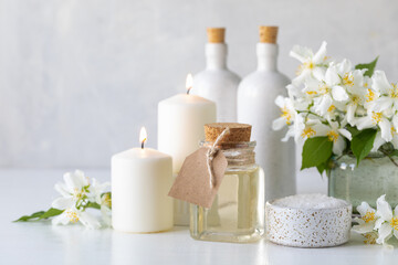 Fototapeta na wymiar Spa concept with jasmine oil, with bath salt and flowers on a white background. Spa and wellness still life. Copy space.