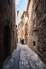 A young man is jumping and having fun in a narrow street in Todi