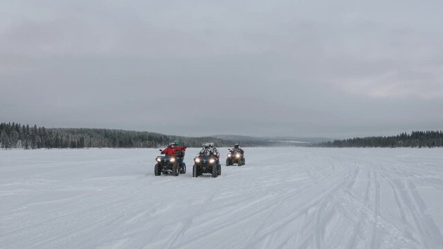 Murmansk region, Russia - January 10, 2021: A group of tourists ride a quadro bikes against the backdrop of a beautiful winter landscape. Slow motion