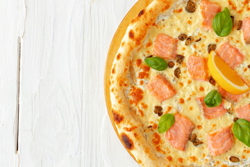 Pizza with baked salmon on wooden table
