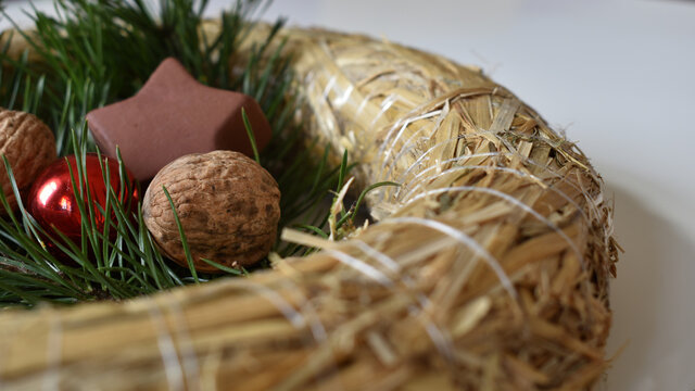 Strohkranz mit N&uuml;ssen, Reisig und braunem Stern aus Keramik vor wei&szlig;em Hintergrund f&uuml;r Weihnachten, Advent, dezente Weihnachtsdekoration