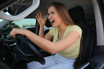 Fototapeta na wymiar Emotional woman in car. Aggressive driving behavior