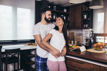 Young couple making breakfast at home. Loving couple having fun in kitchen.