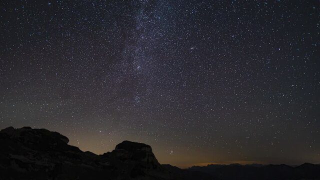 time lapse in 4k high up in the mountains during the night with sky full of stars, the milkyway and some perseids and clouds
