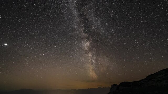 4k time lapse of night sky high up in the mountains with sky full of stars and milkyway some clouds passing by also planet venus visible
