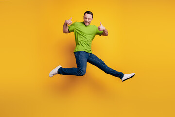 Fototapeta na wymiar Portrait of funky excited guy jump raise thumb up have fun on yellow wall