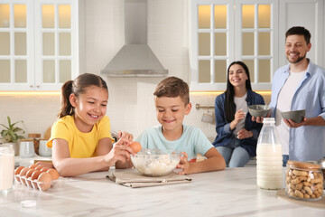 Happy family cooking together at table in kitchen. Adoption concept