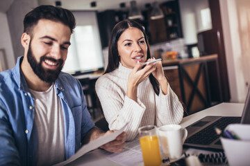Young couple using a laptop and digital tablet together working at home