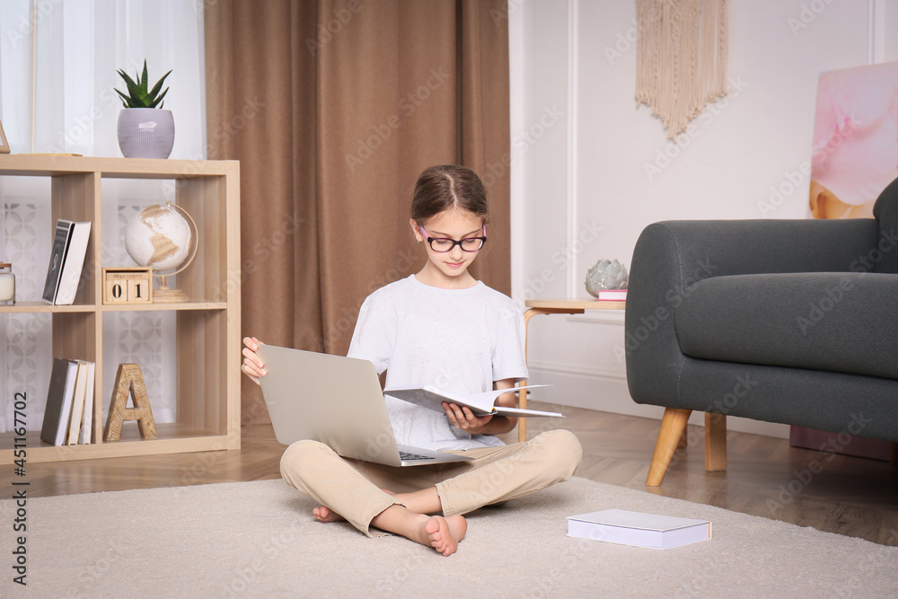 Wall mural Girl with laptop and books sitting on floor at home