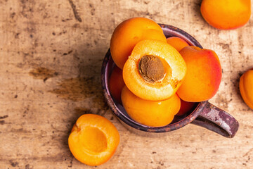 Ripe apricots in a vintage iron mug on a wooden table
