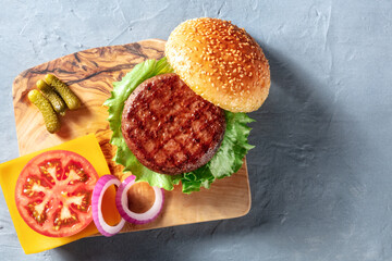 Hamburger ingredients, shot from above on a blue background with a place for text. Sesame bread,...