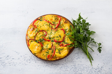 Potato tortilla with bell peppers and herbs on a light gray textured background, top view. Delicious homemade breakfast or snack. Traditional Spanish food